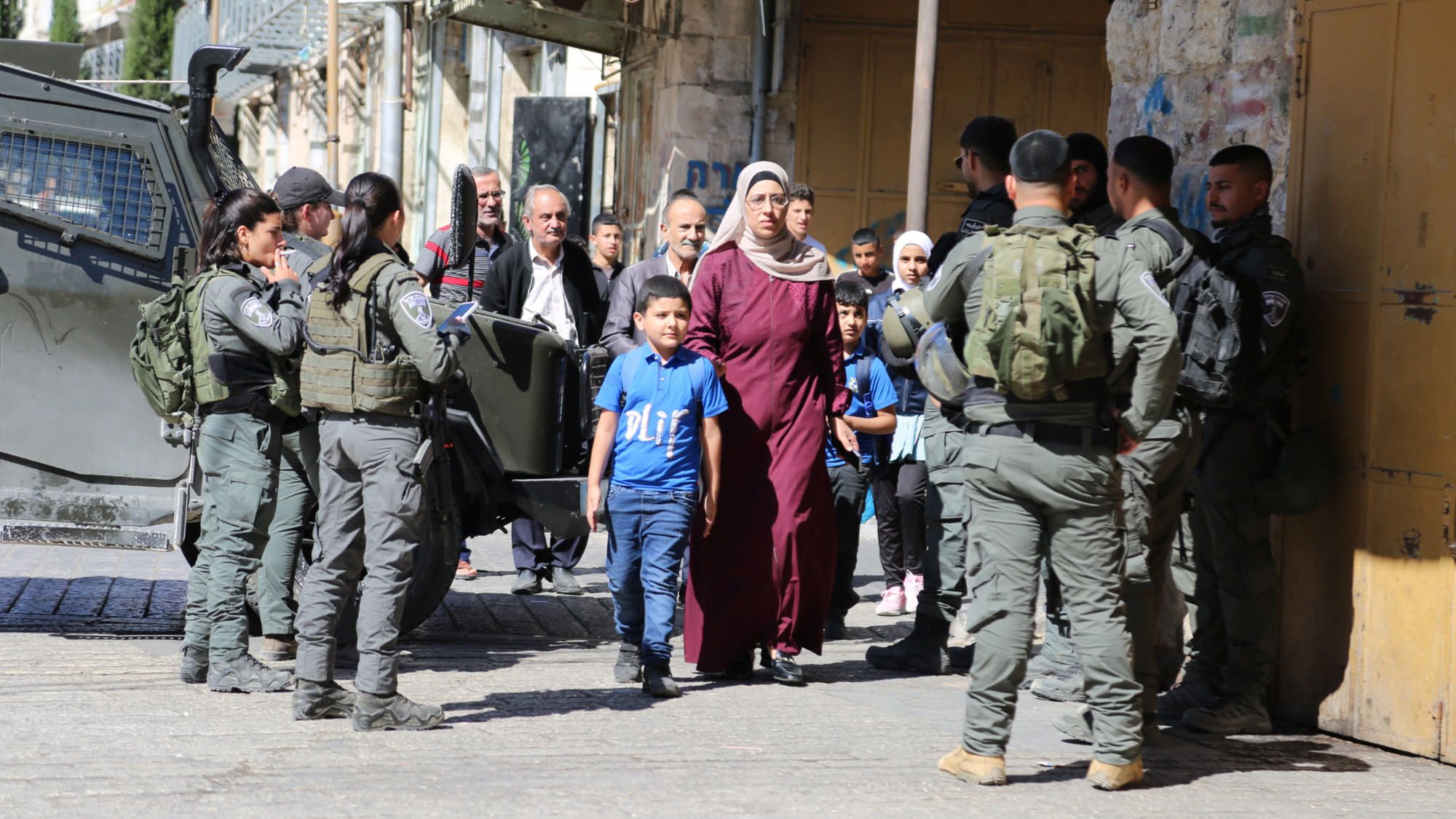 Palestinians forced to pass through a group of Israeli soldier in Hebron in the occupied West Bank (MEE/Mosab Shawar)