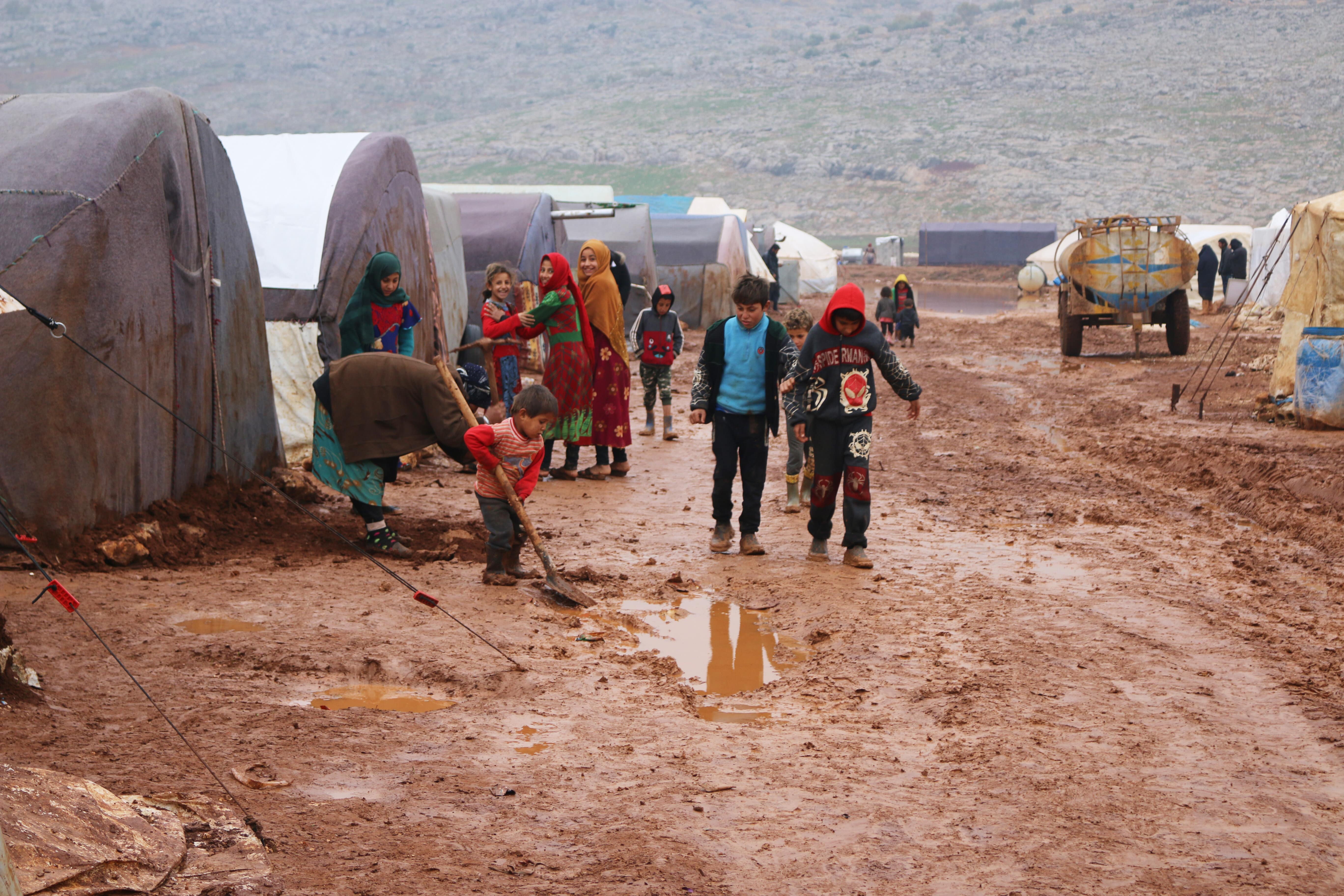 A family tries to clear waste from their flooded camp