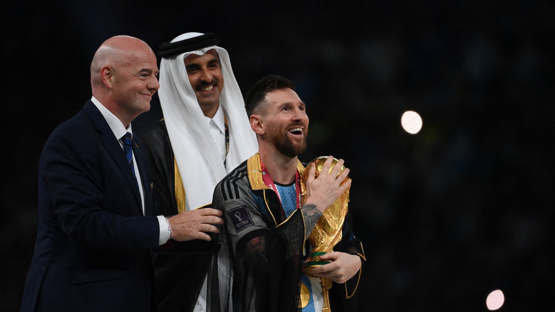 Argentina's forward #10 Lionel Messi holds the World Cup trophy after receiving it from FIFA President Gianni Infantino and Qatar's Emir Sheikh Tamim bin Hamad al-Thani during the Qatar 2022 World Cup trophy ceremony 