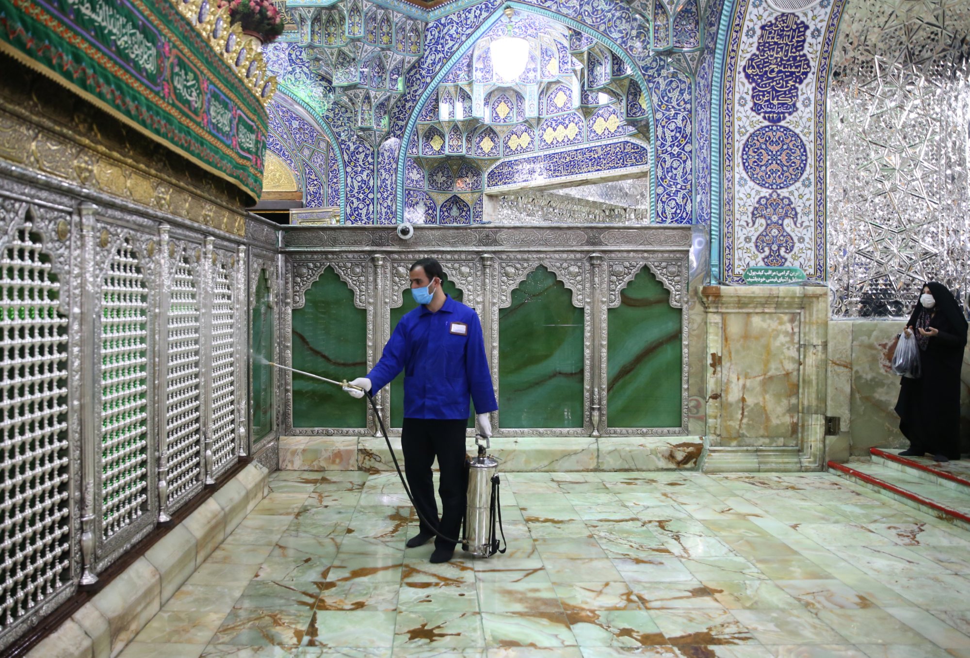 Un agent sanitaire iranien désinfecte le sanctuaire Fatima Masoumeh de Qom le 25 février 2020 pour empêcher la propagation du COVID-19 (AFP)