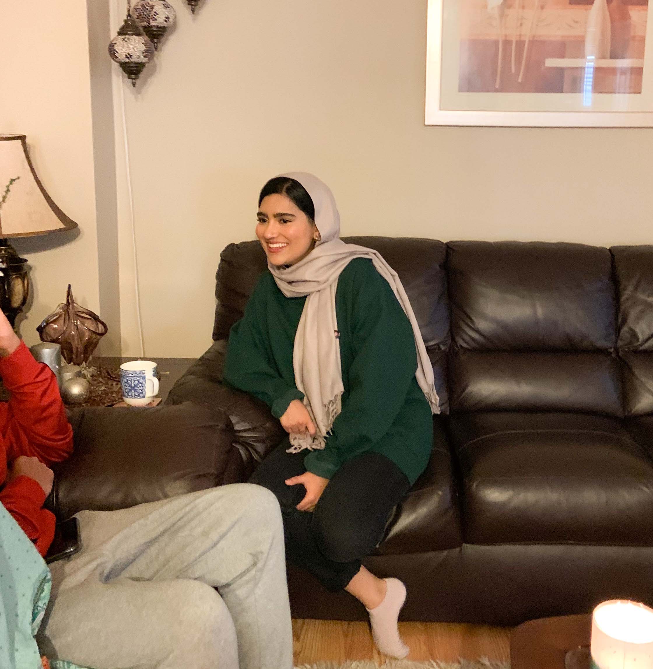 Rabia Moin is sitting on a sofa next to her family.