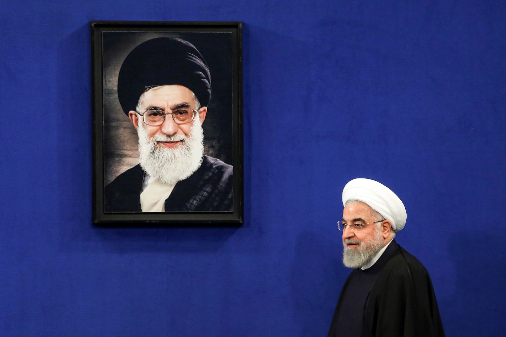 Iranian President Hassan Rouhani walks past a portrait of Supreme Leader Ayatollah Ali Khamenei in Tehran on 16 February (AFP)