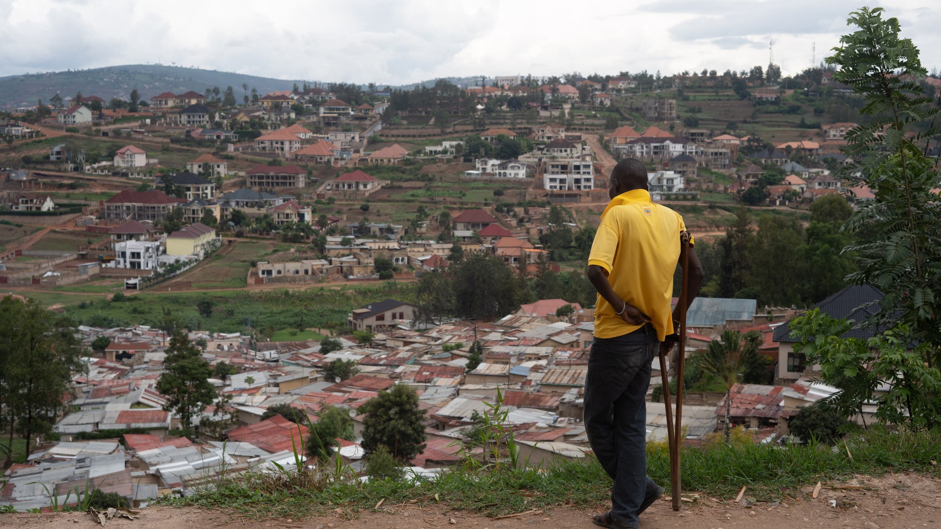 A man with a crutch overlooks a slum on the outskirts of Kigali on 17 October, 2019 (AFP)