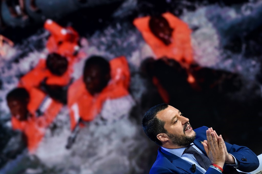 Italy's Interior Minister and Deputy Prime Minister Matteo Salvini speaks during the Italian talk show "Porta a Porta", broadcast on Italian channel Rai 1, in Rome, on June 20, 2018, as picture of migrants is seen in the background. 