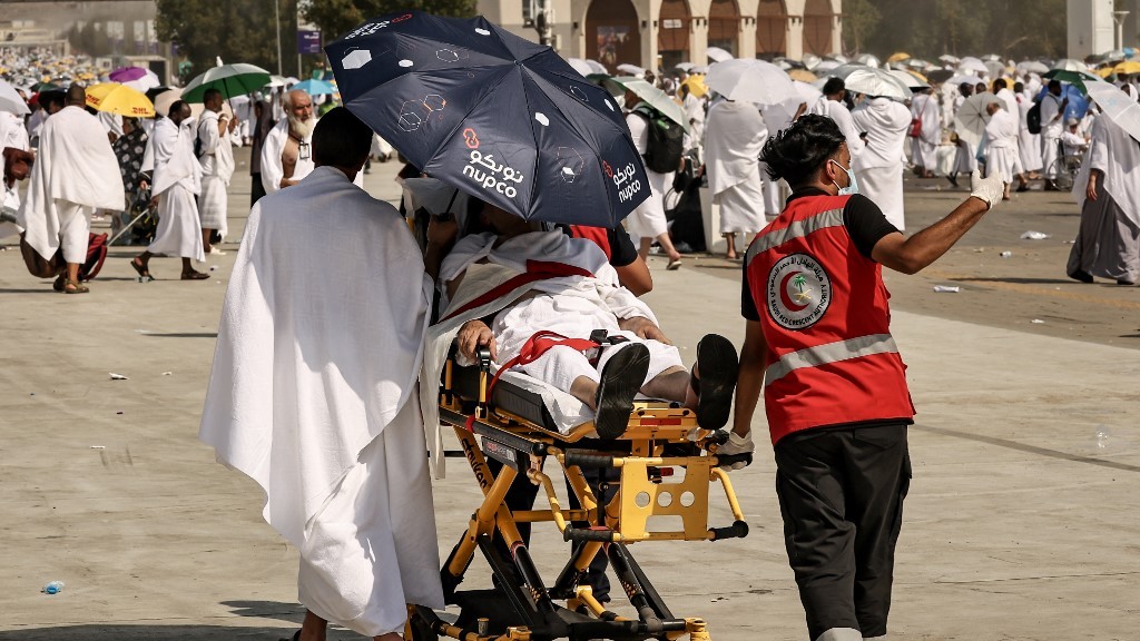 Medical team members evacuate a pilgrim affected by the scorching heat, at the base of Mount Arafat during the annual hajj pilgrimage on 15 June (AFP)