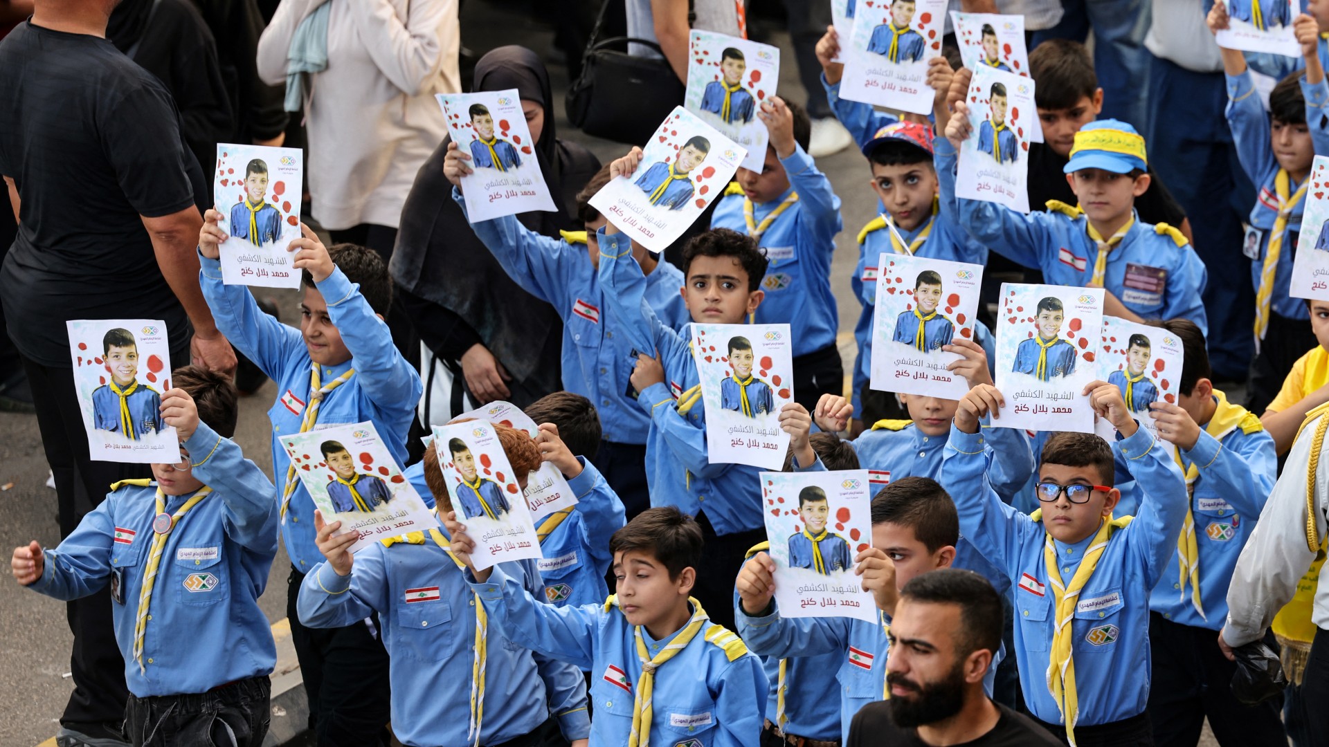 Boy scouts raise the picture of a fellow scout killed by an exploding pager, during the funeral procession in Beirut 18 September (AFP/Anwar Amro)