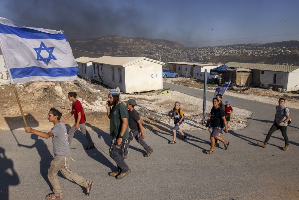Israeli settlers march in a new outpost in the occupied West Bank on 21 June 2021 (AFP)