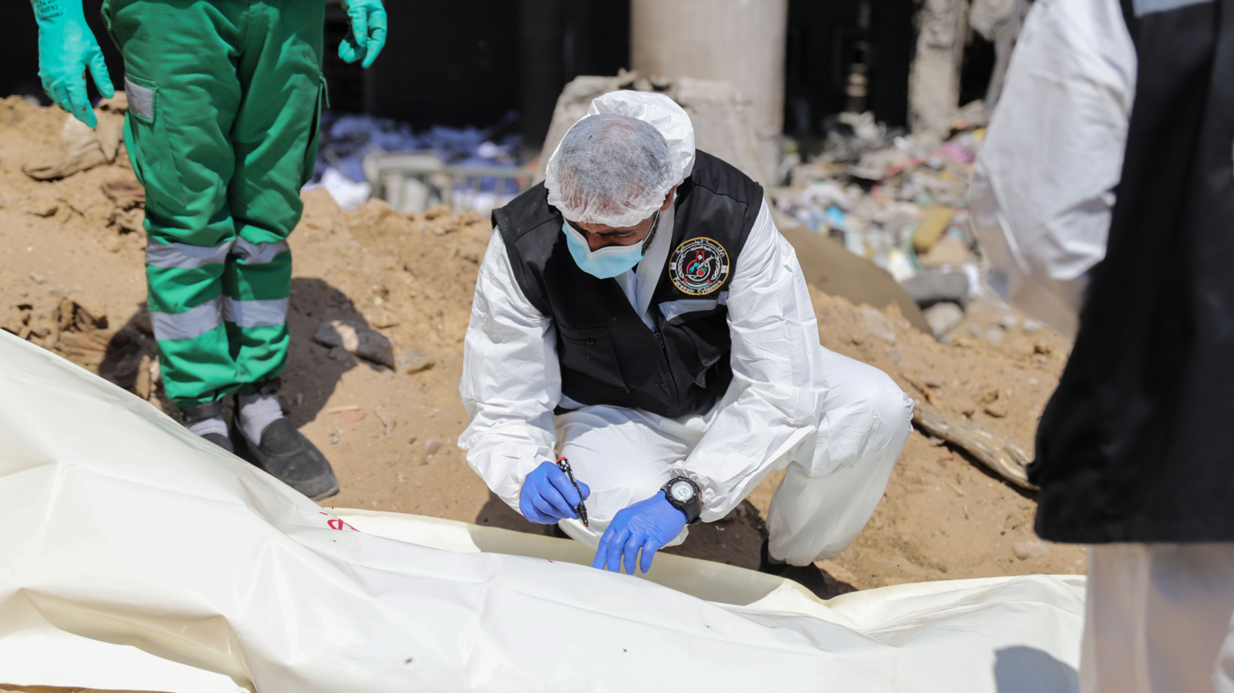 A forensic team write on the shroud of one of the recovered bodies in al-Shifa hospital on 8 April, 2024 (Mohammed al-Hajjar/MEE)