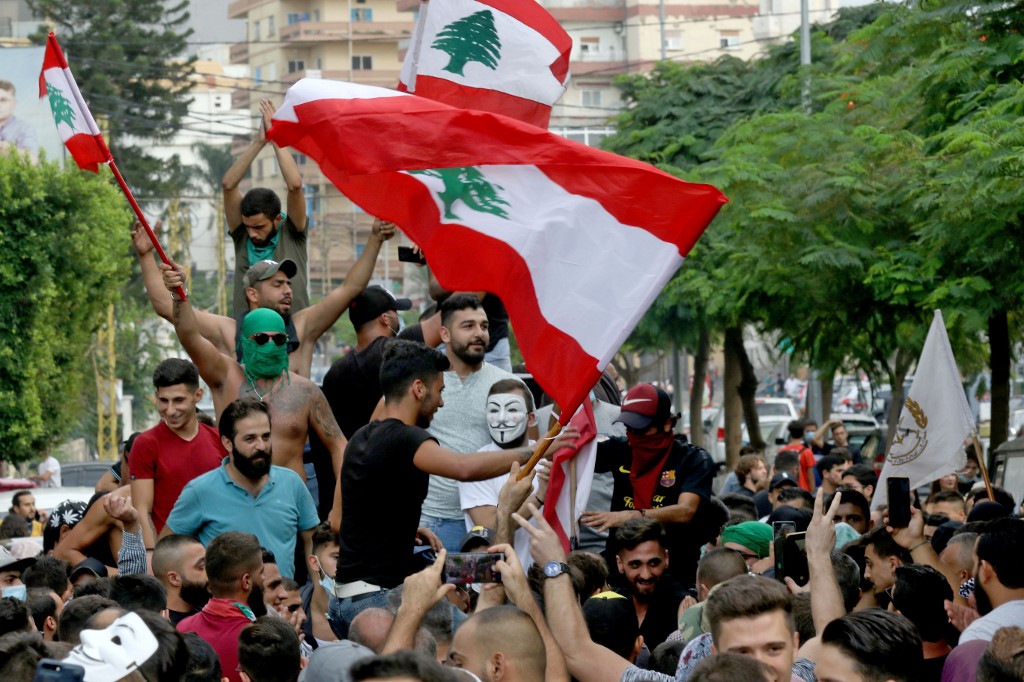 Demonstrators wave Lebanese flags in the southern city of Sidon on 18 October 2019 (AFP)