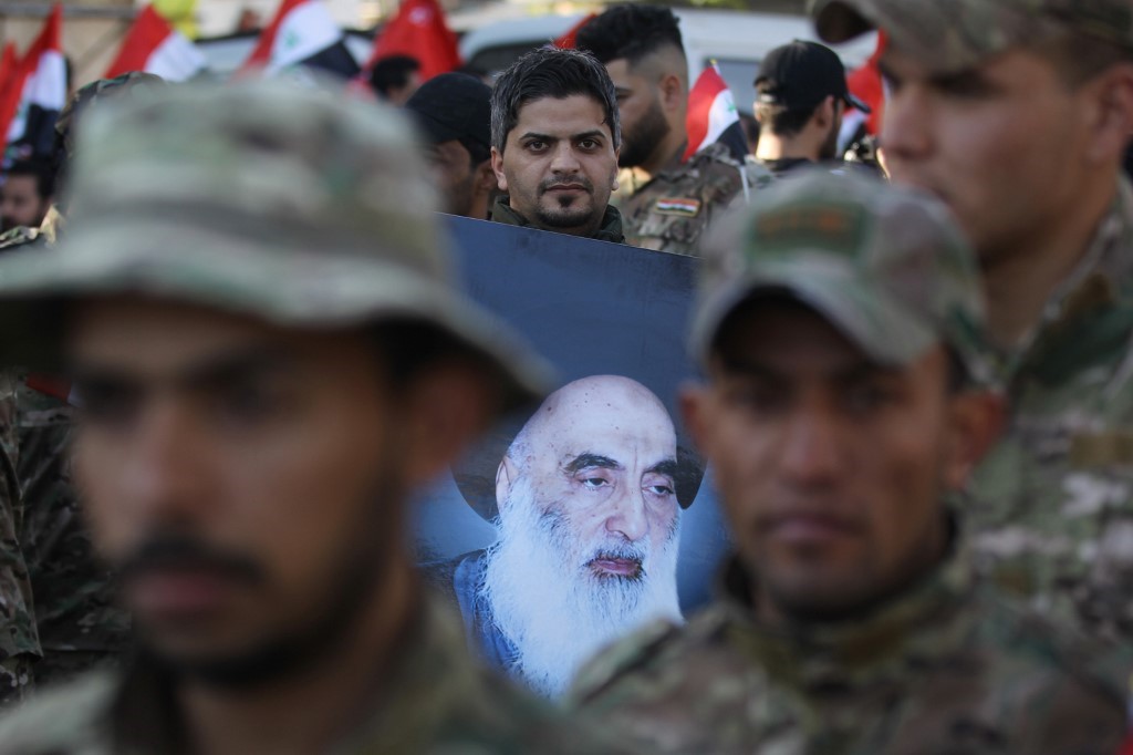A member of Hashed al-Shaabi holds a picture of Iraq's top Shiite cleric Grand Ayatollah Ali Sistani during the funeral procession of fellow comrades in Baghdad on December 31, 2019,