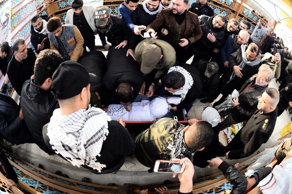 Iraqi mourners, including members of Hashed al-Shaabi, gather around the coffin of Muhandis in Najaf on Wednesday (AFP)