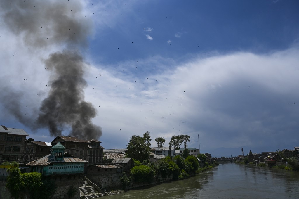 Smoke rises from a house at the site of a gun battle between suspected militants and government forces in downtown Srinagar on 19 May (AFP)
