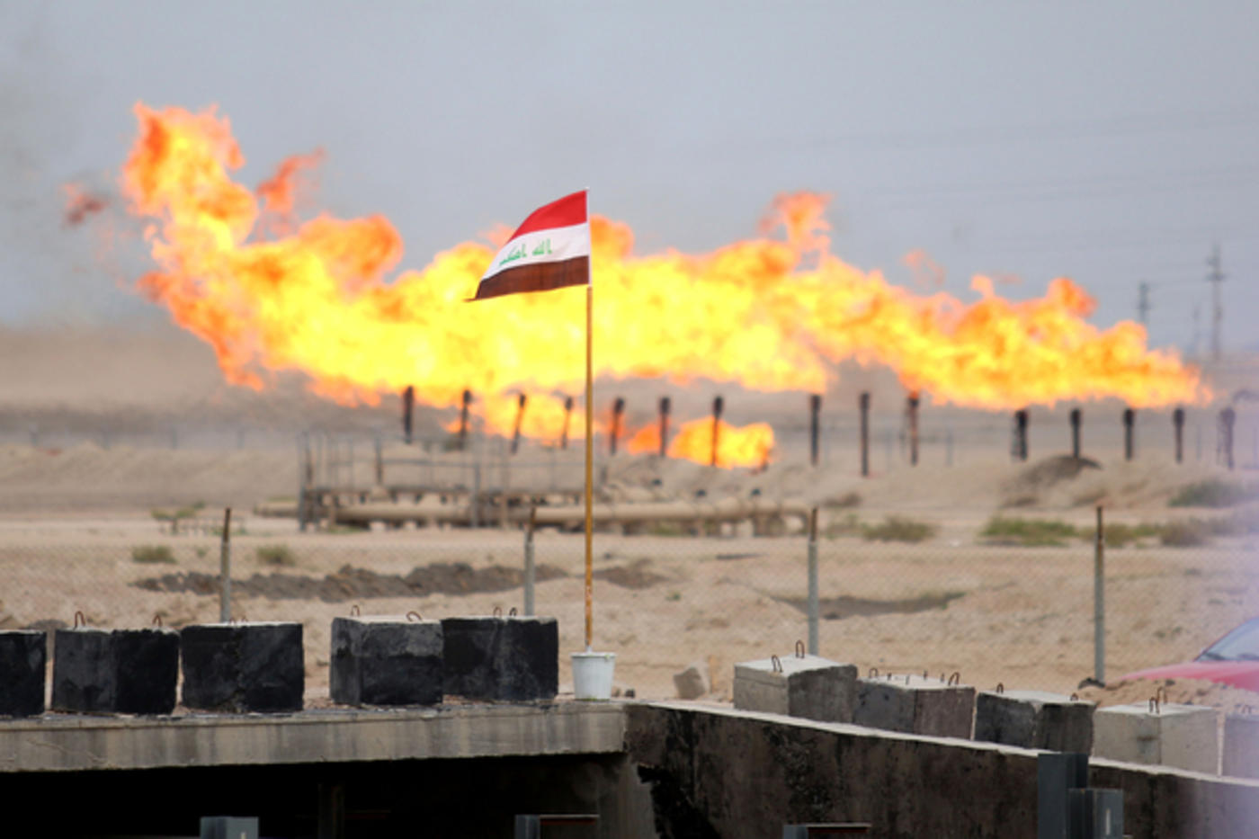 An Iraqi flag flies outside an oil refinery in the country’s south in 2016 (AFP)
