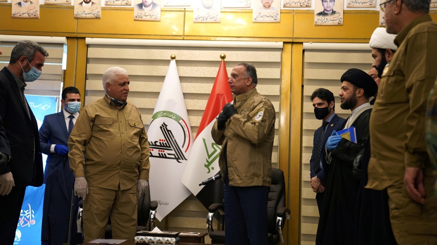 Iraqi Prime Minister Mustafa al-Kadhimi wears a uniform of the Popular Mobilisation forces during a meeting with PMF head Faleh al-Fayyad in May (Reuters)