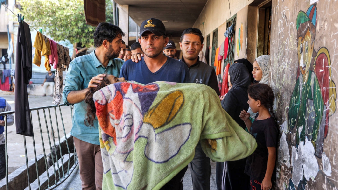 A man carries the body of a Palestinian girl killed in an Israeli bombardment on the Rafei school shelter in the Jabalia camp, northern Gaza, on 9 October 2024