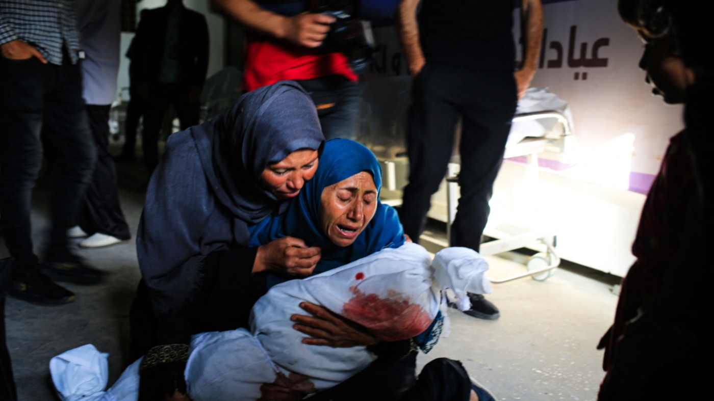 A Palestinian woman holds the shrouded body of a child killed in an Israeli bombardment, in Rafah, southern Gaza in May 2024