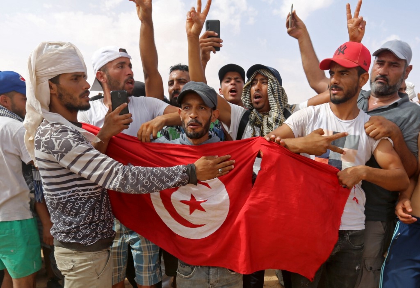 Des manifestants agitent le drapeau tunisien pendant un sit-in sur un site de production de pétrole à El Kamour, dans le sud du pays, le 16 juillet 2020 (AFP)