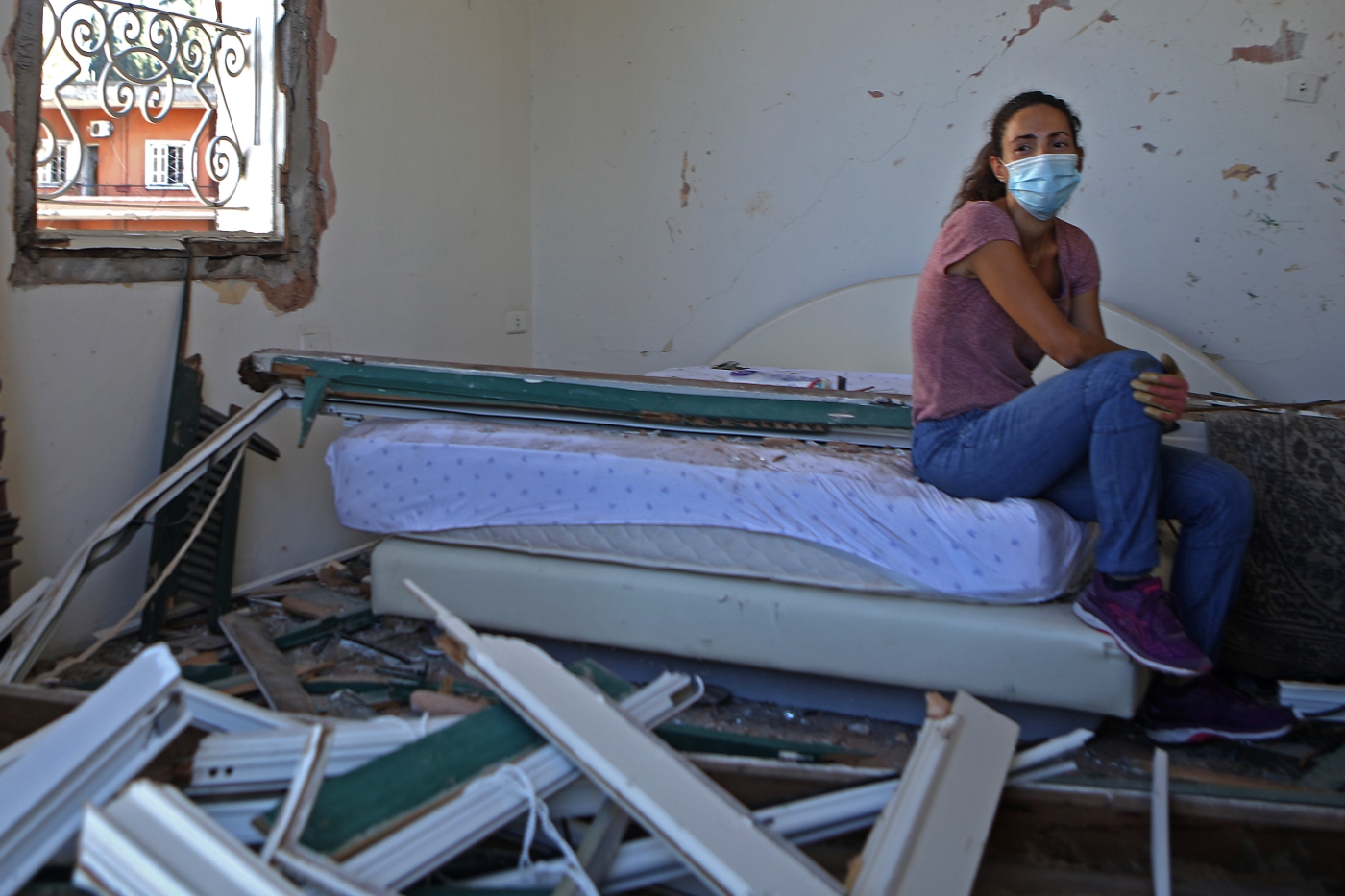 A Lebanese woman sits in her damaged bedroom in the damaged neighbourhood of Mar Mikhael in Beirut on 6 August (AFP)
