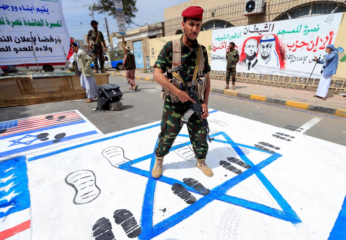 A fighter loyal to Yemen's Huthi rebels treads on US and Israeli flags painted on the ground during a rally in the capital Sanaa, on August 22, 2020 (AFP)