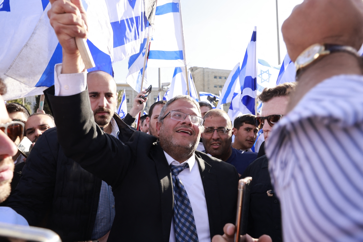Israeli far-right lawmaker and leader of the Jewish Power party Itamar Ben-Gvir, raises an Israeli flag in Safra square in Jerusalem on 20 April 2022 (AFP)