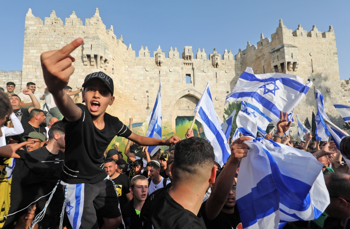 Demonstrators gesture as they gather with Israeli flags during the 'flag march' outside the Old City's Damascus Gate on 29 May (AFP)