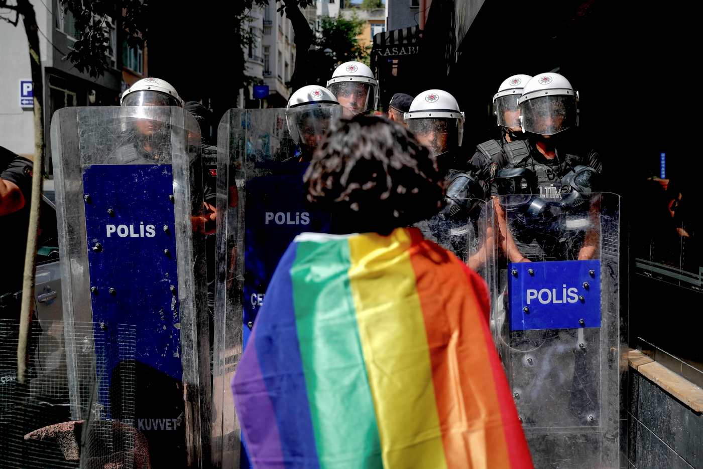 A participant faces riot policemen wearing a rainbow flag during a Pride march in Istanbul, on June 26, 2022. (AFP)