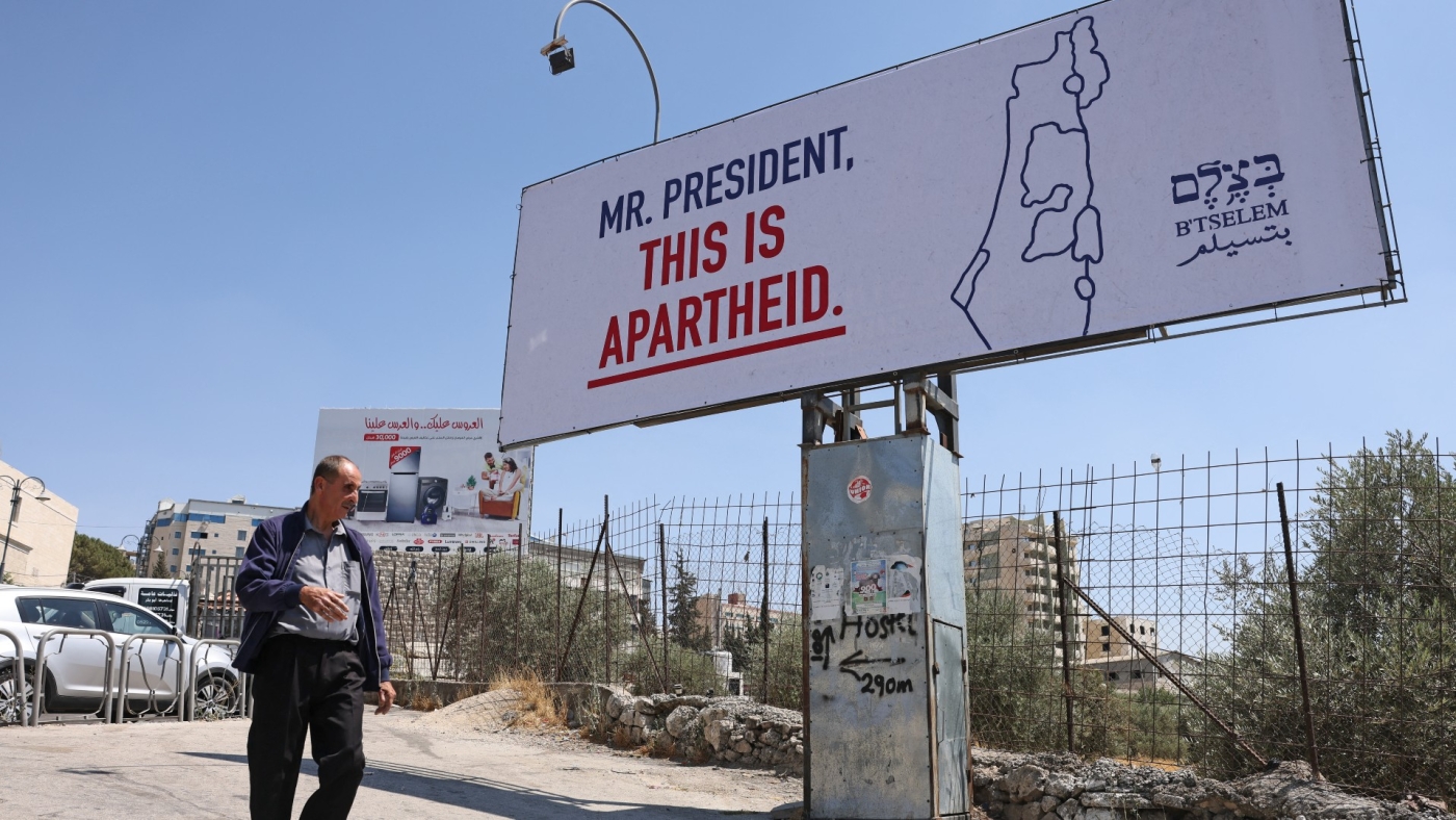 A man walks past a billboard, part of a campaign organised by Israeli rights group B'Tselem, in the West Bank city of Bethlehem on 13 July 2022, ahead of the US Ppresident's arrival for an official visit (AFP)