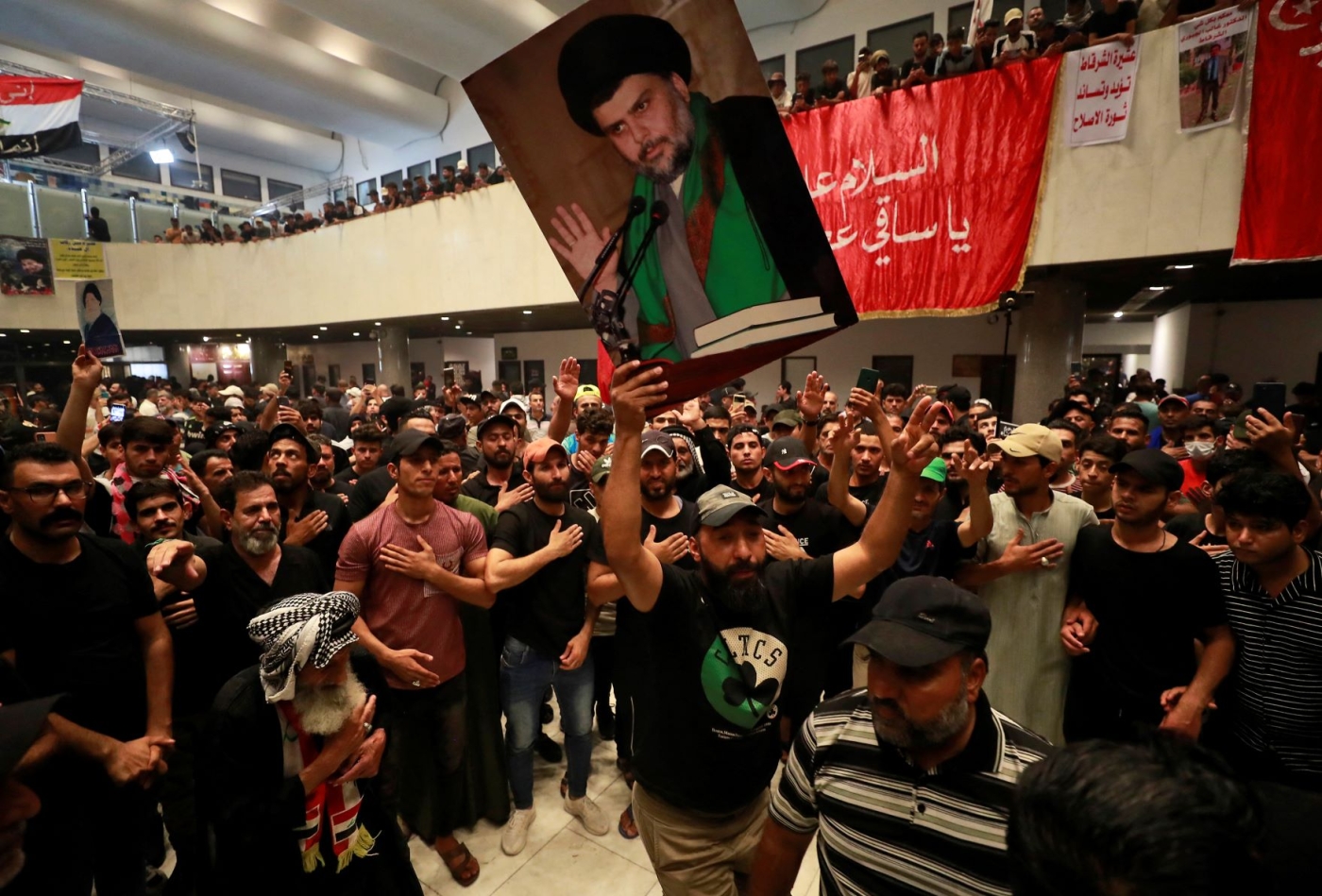 Supporters of Iraqi cleric Moqtada Sadr (portrait), protesting against a rival political bloc's nomination for prime minister, occupy Iraq's parliament in the capital Baghdad's high-security Green Zone, on August 1, 2022 (AFP)