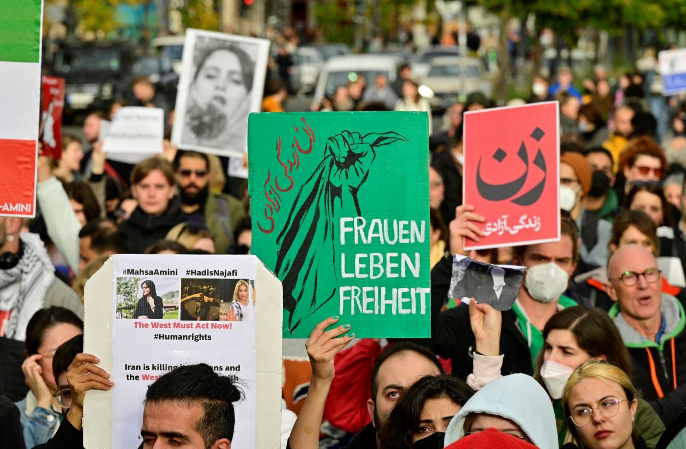 Demonstrators hold placards in support of women and the Iranian protesters, on September 28, 2022 near Berlin's landmark Brandenburg Gate (AFP)