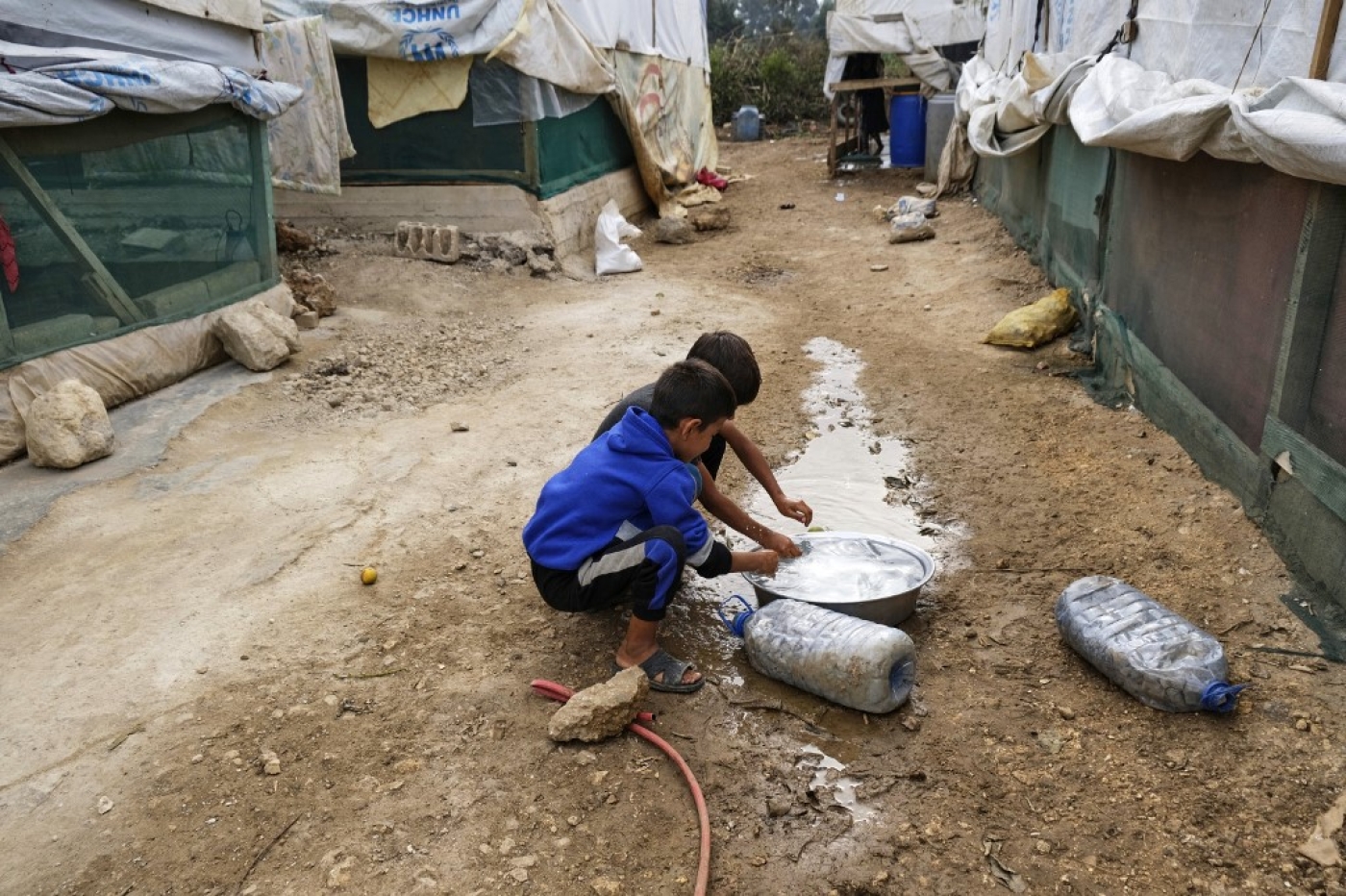 Des enfants se rincent les mains dans une bassine remplie d’eau dans un camp de fortune pour réfugiés syriens à Talhayat dans le district d’Akkar au nord du Liban, le 26 octobre 2022 (AFP/ Ibrahim Chalhoub)