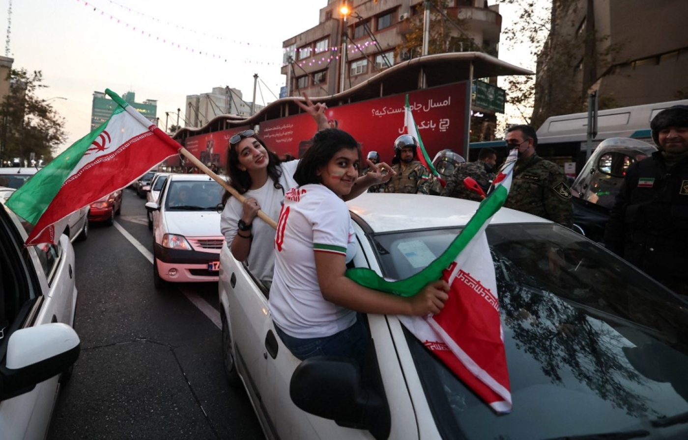 Des femmes iraniennes, sans voile, agitent le drapeau national à Téhéran après la victoire de leur équipe de football contre le Pays de Galles lors de la Coupe du monde Qatar 2022, le 25 novembre 2022 (AFP/Atta Kenare)
