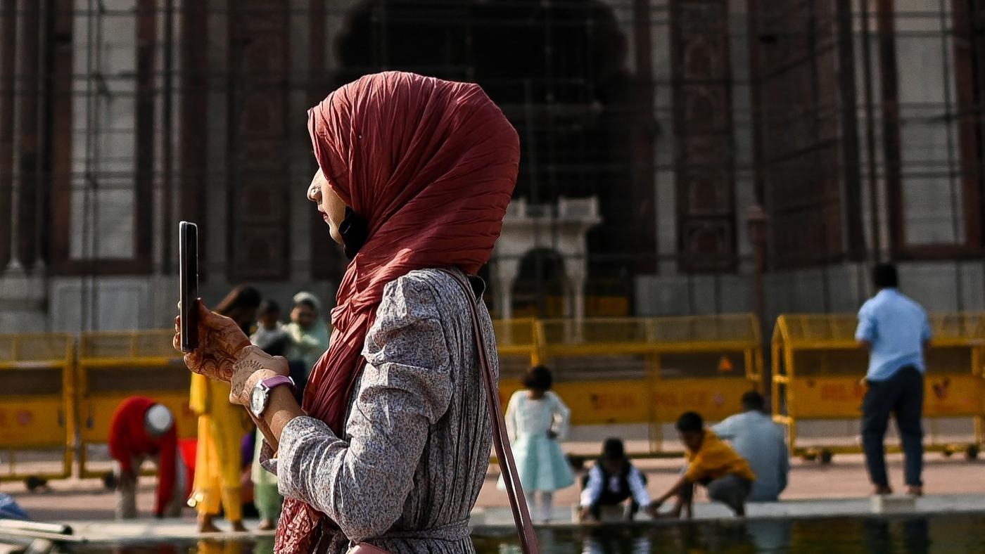 Une femme prend une photo avec son téléphone en visitant la mosquée Jama Masjid, dans la ville fortifiée de New Delhi, le 26 novembre 2022 (AFP)