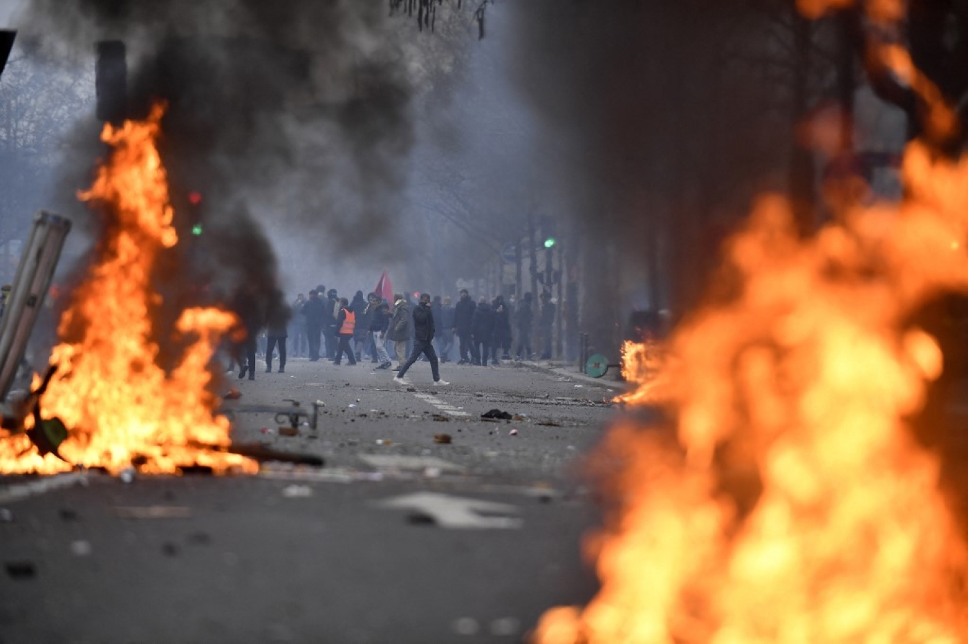 Protesters stand behind flames during clashes following a demonstration a day after a gunman opened fire at a Kurdish cultural centre killing three people, at The Place de la Republique in Paris on 24 December 2022 (AFP)