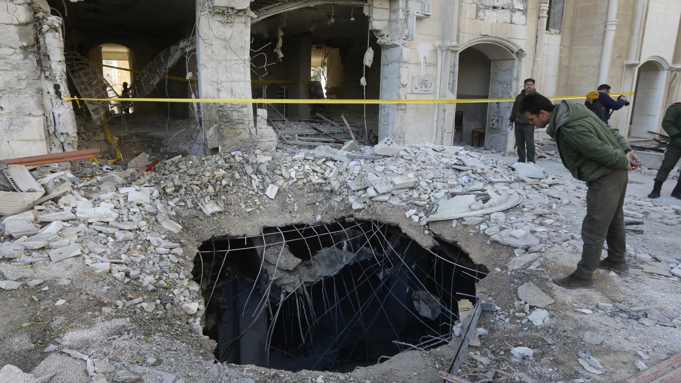 A member of the Syrian security forces checks a crater caused by a reported Israeli missile strike in Damascus, on 19 February 2023 (AFP)
