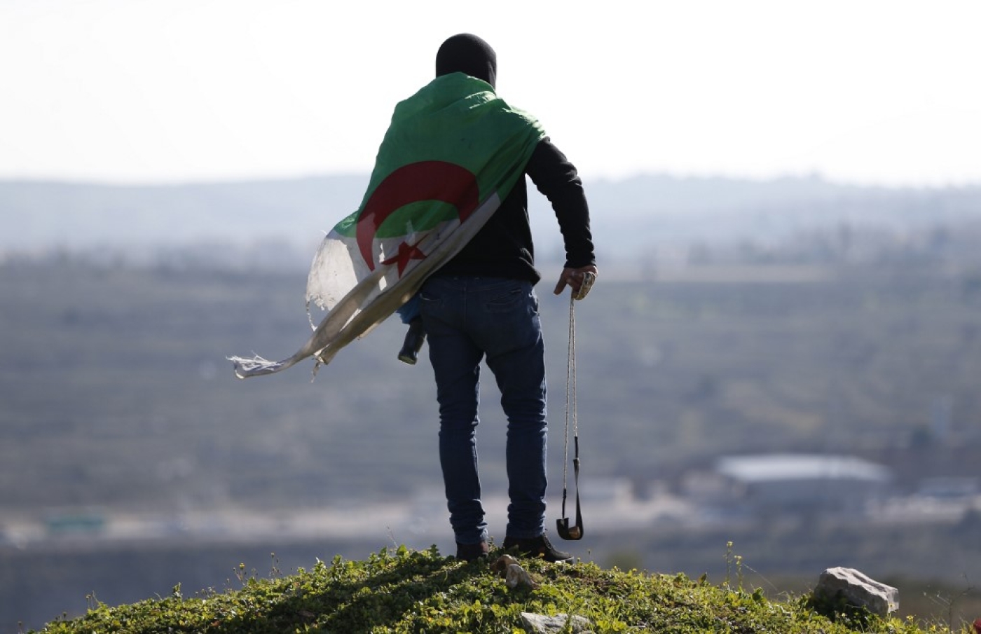 Un manifestant palestinien couvert du drapeau algérien, lors d’affrontements avec les forces israéliennes, le 12 février 2016 en Cisjordanie occupée (AFP) 