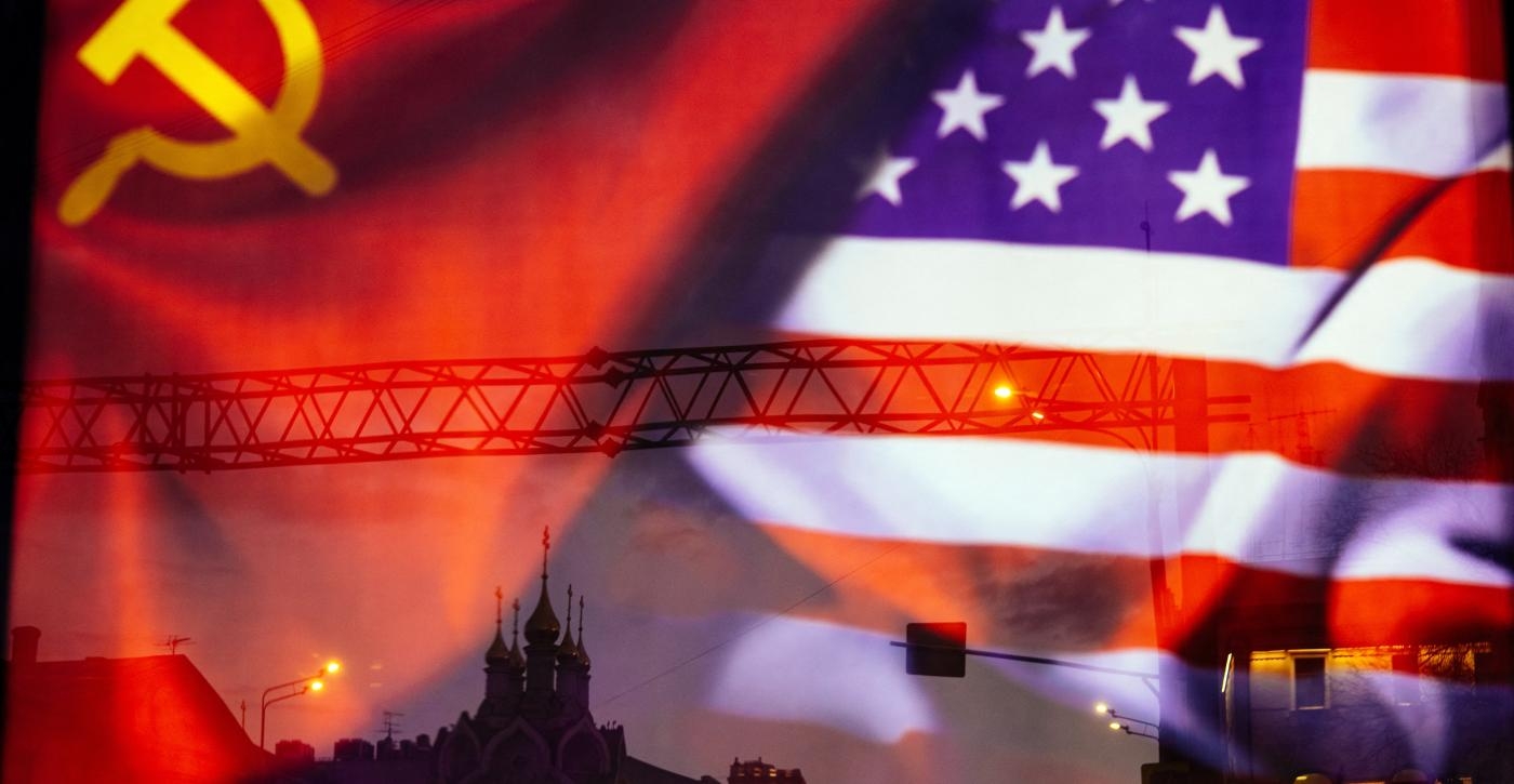 Une rue de Moscou se reflète sur une affiche où apparaissent les drapeaux soviétique et américain, le 23 mars 2021 (AFP)