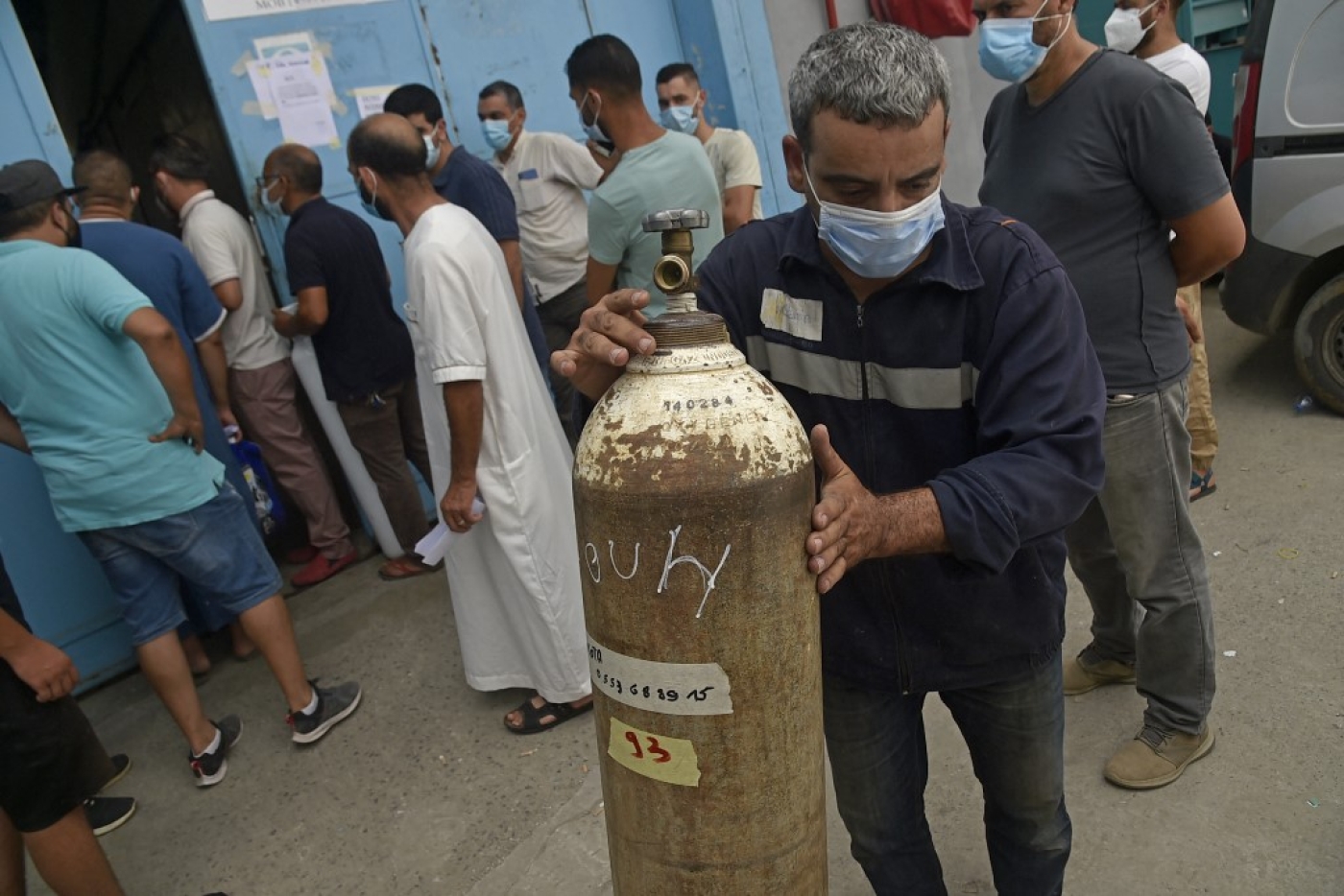 Des Algériens attendent de recevoir des bouteilles d’oxygène offertes par une entreprise privée pour les patients atteints de COVID-19 dans la ville de Blida (nord), le 28 juillet 2021 (AFP/Ryad Kramdi)