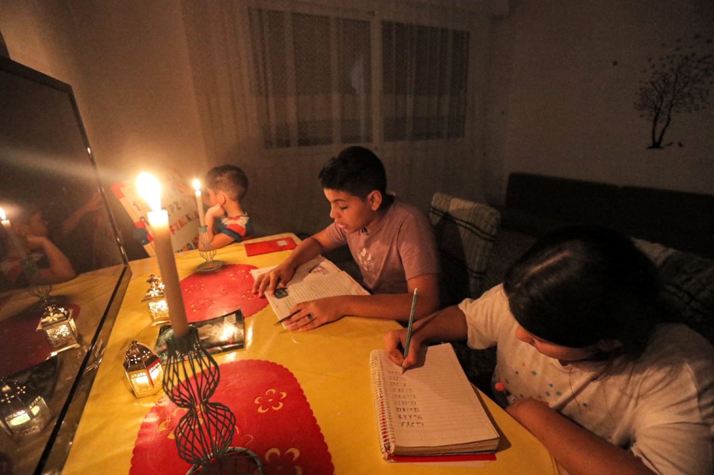 Des enfants, à Tripoli, font leurs devoirs à la lumière des bougies, le 26 août 2021 (AFP/Mahmud Turkia) 