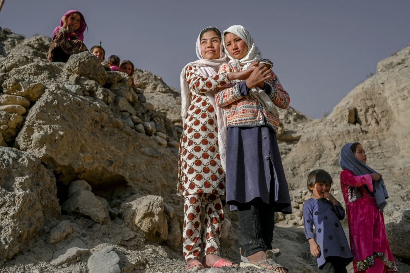 Des enfants de l’ethnie Hazara se tiennent sur une falaise creusée de grottes où les gens vivent encore comme il y a des siècles à Bamiyan, en Afghanistan, le 3 octobre 2021 (AFP/Bulent Kilic)
