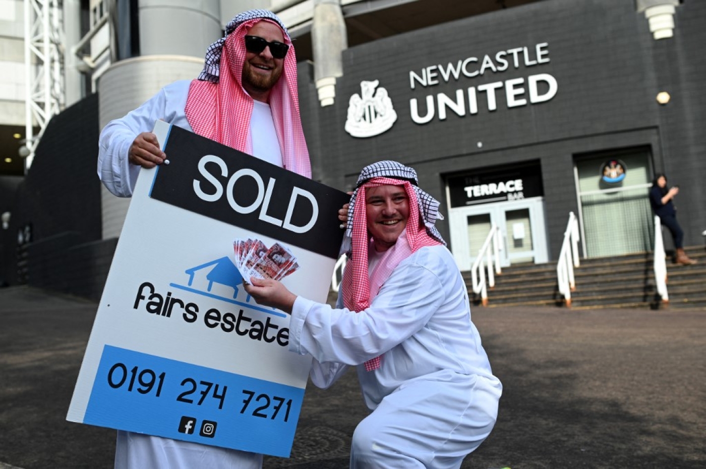 Des supporteurs de Newcastle, vêtus comme des Saoudiens, fêtent la vente de leur club à l’Arabie saoudite (AFP/Oli Scarff)