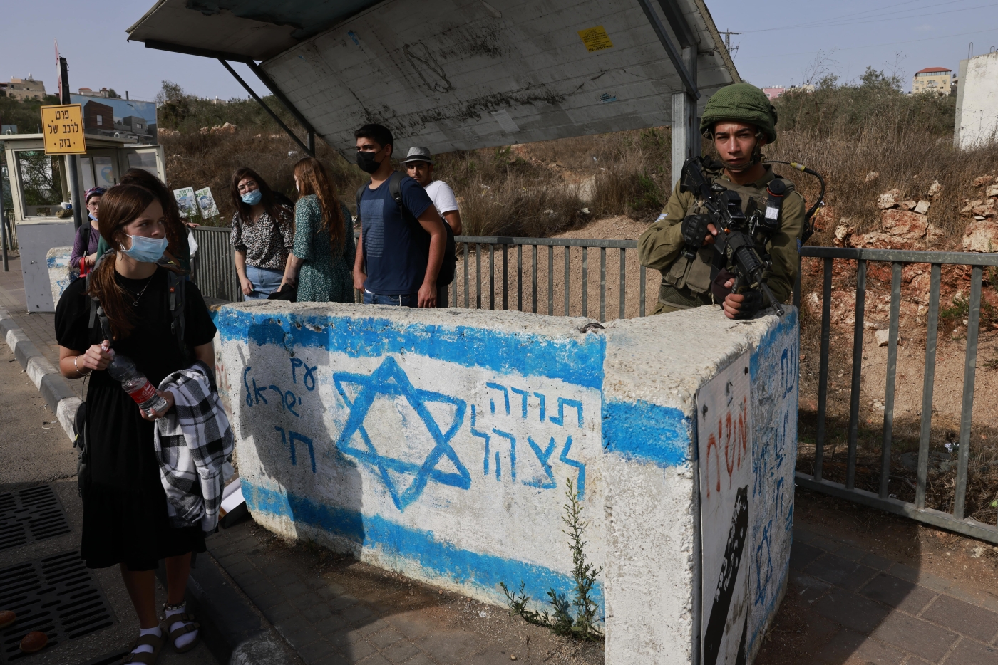 An Israeli soldier on guard at a bus station near the Jewish settlement of Ariel in the occupied West Bank on 14 October 2021 (AFP)