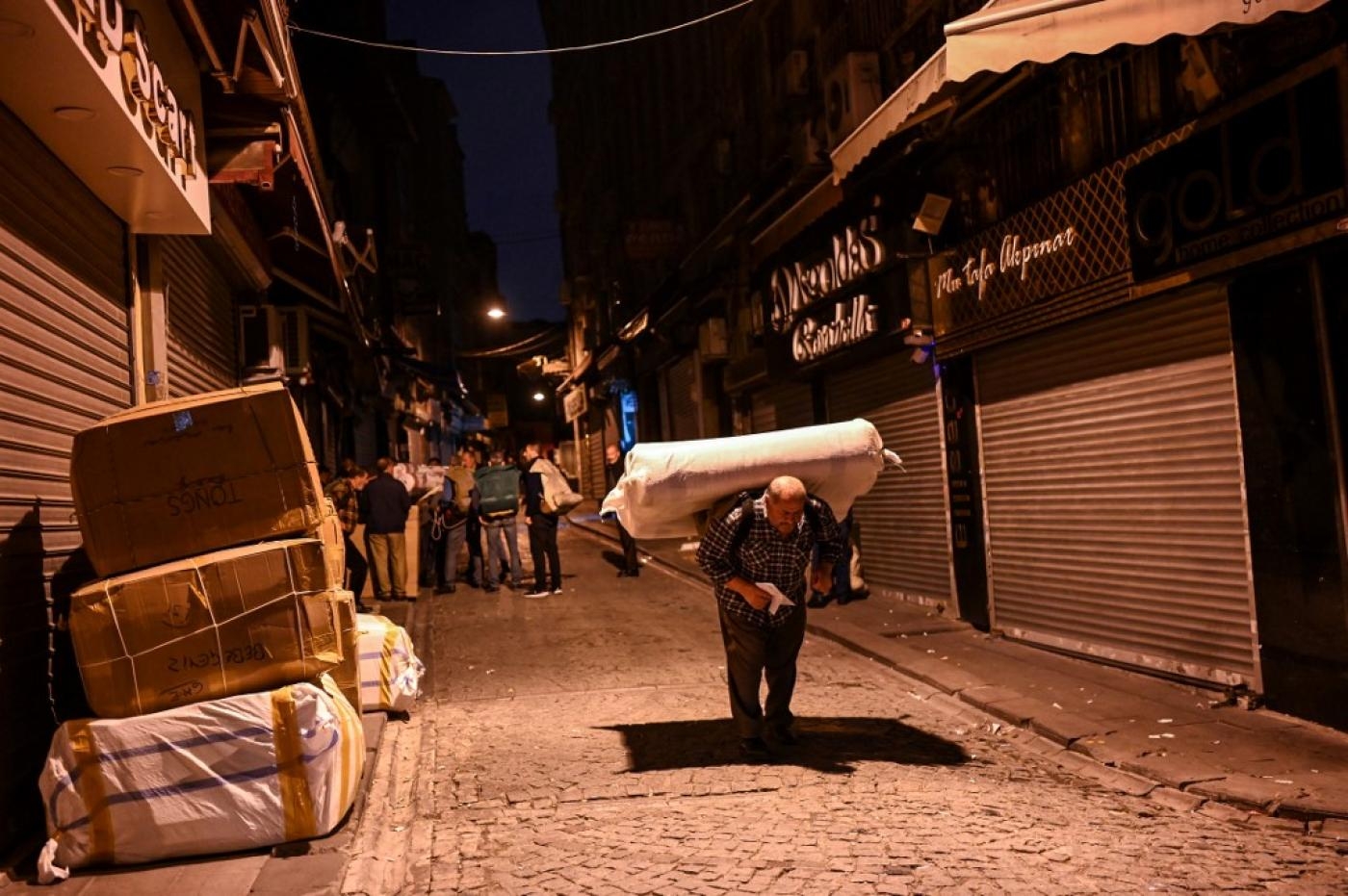 Un porteur transporte des marchandises alors que d’autres attendent leur tour, au petit matin près du grand bazar à Istanbul, le 28 octobre 2021 (AFP)
