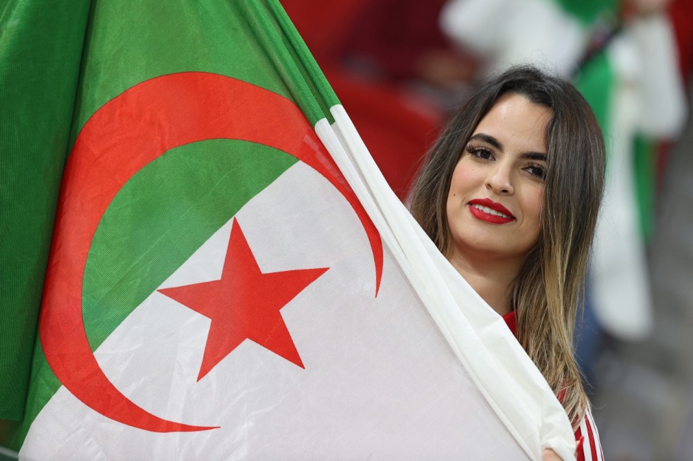Une Algérienne secoue le drapeau de son pays, lors de la demi-finale de la Coupe arabe entre l’Algérie et le Qatar, le 15 décembre 2021 (AFP/Karim Jaafar)