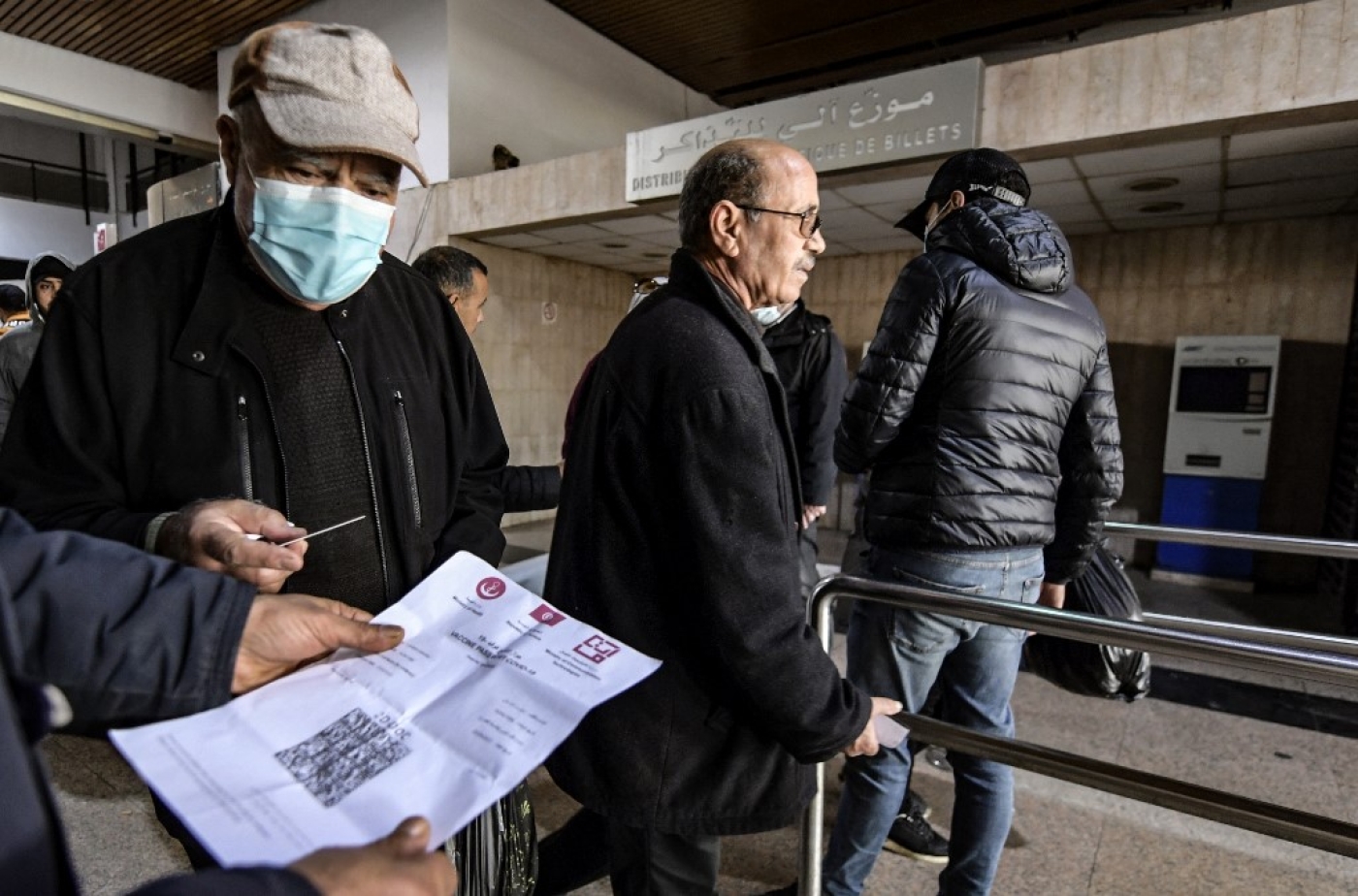 Un employé des transports publics tunisiens contrôle le pass vaccinal d’un passager à l’entrée d’une gare de la capitale Tunis, le 22 décembre 2021 (AFP/Fethi Belaid)