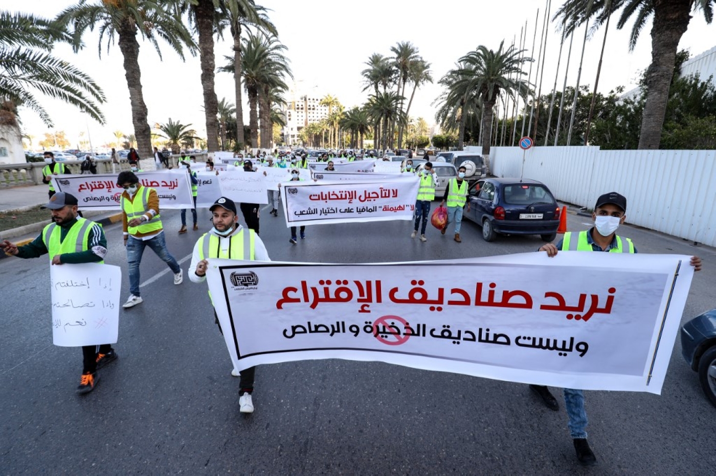 De jeunes militants libyens manifestent contre le report des élections présidentielles sur la place des Martyrs de la capitale Tripoli, le 25 décembre 2021. La banderole dit en arabe : « Nous voulons des urnes, pas des boîtes de munitions ». (AFP/Mahmud Turkia) 
