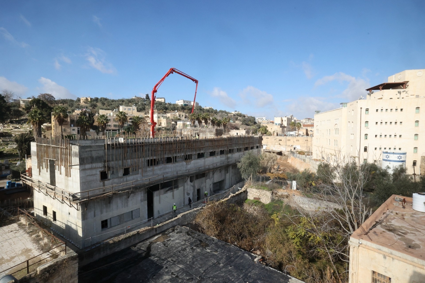 Builders work on new constructions in a settlement zone in the occupied West Bank's Hebron (AFP)