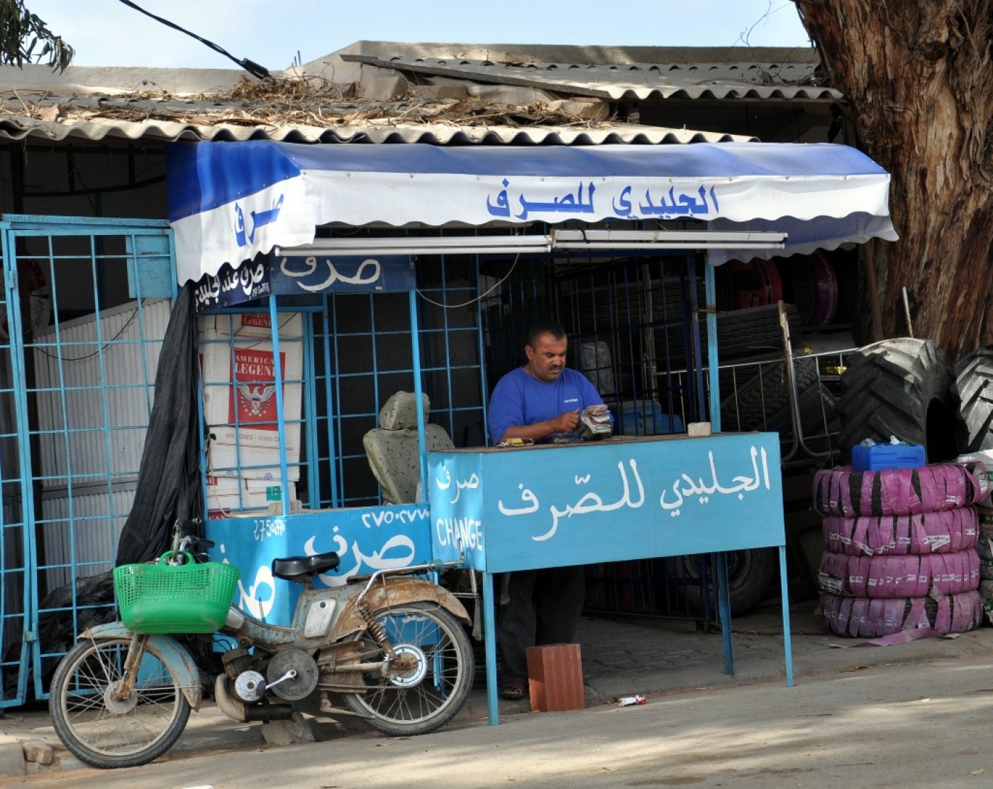 Un épicier tunisien gère son propre service de change au souk de Ras Jedir, à la frontière avec la Libye (AFP)