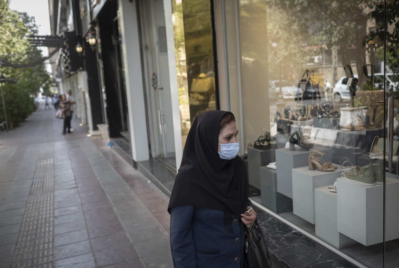 An Iranian woman walks past a shop window in northern Tehran on 9 July 2022 (Reuters)