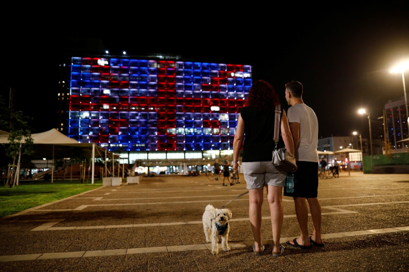 Des promeneurs s’arrêtent avec leur chien sur la place Rabin de Tel-Aviv, face à la mairie illuminée aux couleurs du drapeau britannique en hommage à la reine Elizabeth II (Reuters)