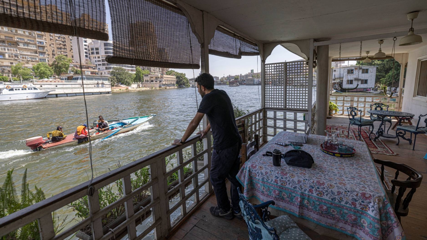 An Egyptian resident stands at the balcony of his houseboat, a community located in the Agouza district on the Giza bank of the Nile river, 27 June 2022 (AFP)